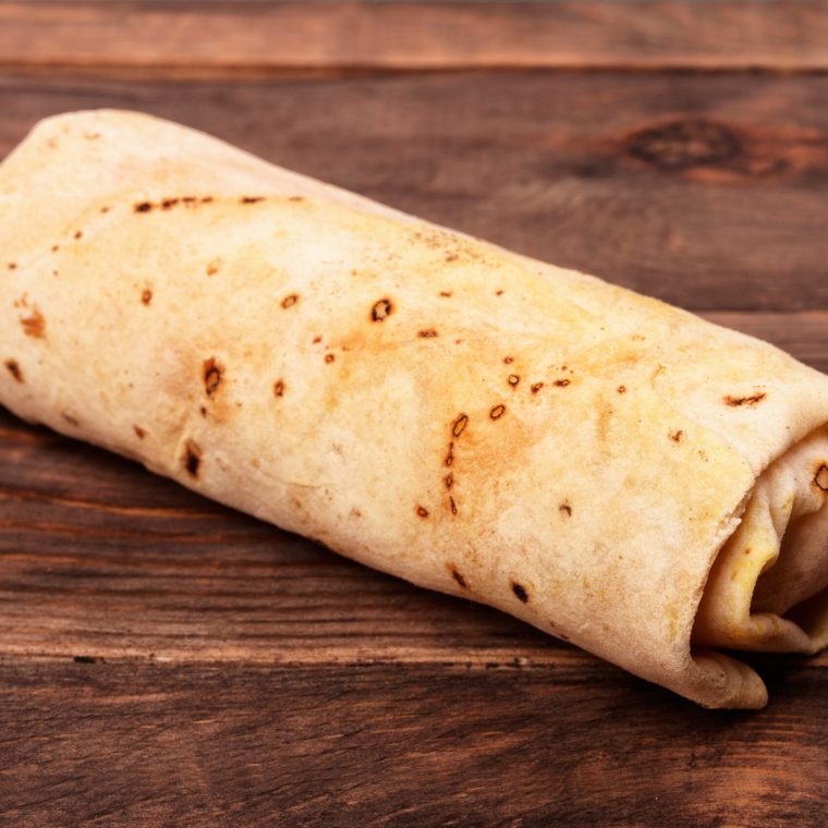 Closed shawurma rolled sandwich on a wooden background